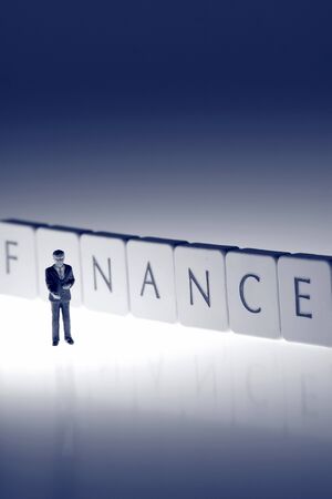 Miniature scale model businessmen on tiles spelling finance shaking hands.の写真素材