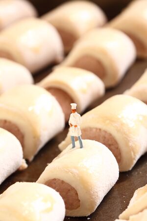 Scale model miniature chef standing on sausage roll.の写真素材