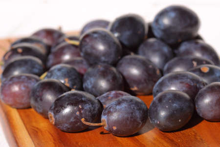 Damsons piled on a wooden chopping board.の写真素材