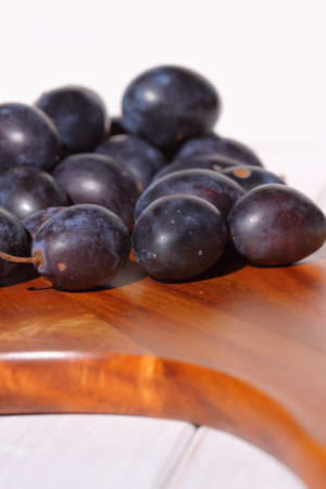 Damsons piled on a wooden chopping board.の写真素材