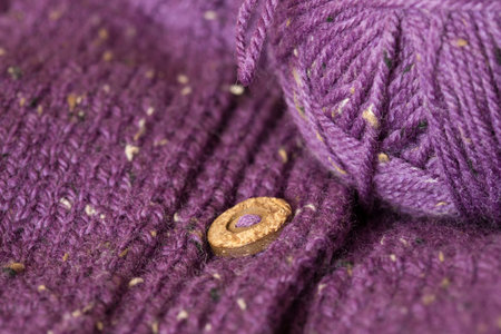 Handmade purple cardigan with wooden buttons with a ball of wool
