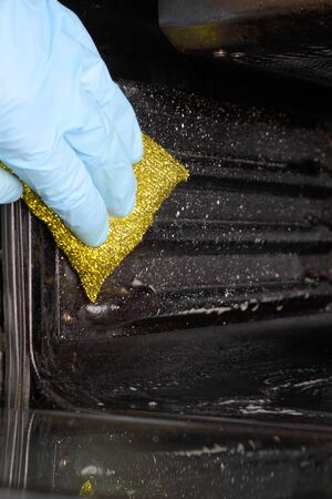 Man wearing gloves cleaning an electric ovenの写真素材