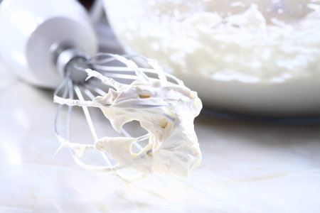 Whisked cream on an electric whisk with a glass bowlの写真素材