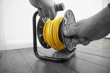 Abstract image of a man winding up an extension cable leadの写真素材