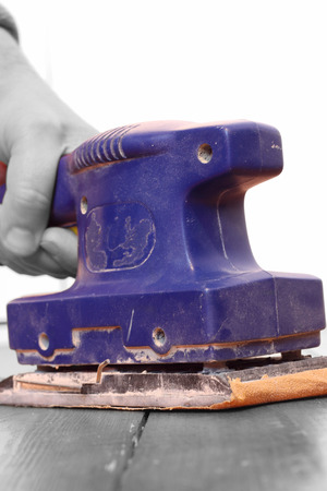 Selective colour image of a man sanding a wooden floorの写真素材