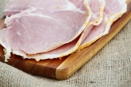 Boiled ham slices on a wooden chopping boardの写真素材