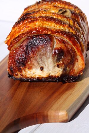 Roast pork with crackling on a wooden chopping boardの写真素材