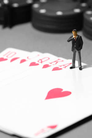 Miniature scale model businessman standing on a poker handの写真素材