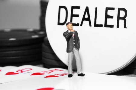 Miniature scale model businessman standing on a poker hand with dealer tokenの写真素材