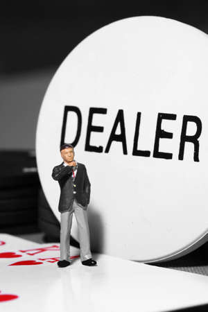 Miniature scale model businessman standing on a poker hand with dealer tokenの写真素材