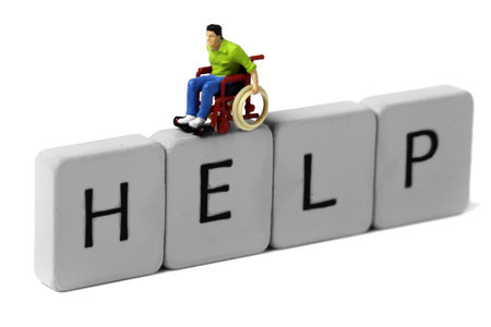 Scale model man in a wheelchair on tiles spelling help