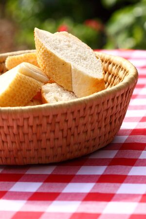 Sliced bread in a woven basket outdoor on a gingham tableclothの写真素材