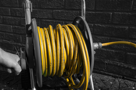 Selective colour image of a man winding a hose pipe reelの写真素材