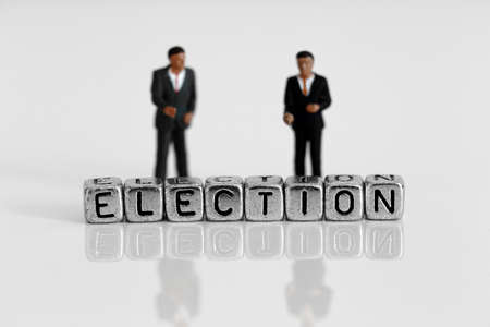 Miniature scale model politicians standing behind the word election on beadsの写真素材