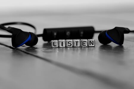 Earphones on a wooden floor with the word listen on beadsの写真素材