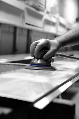 Man using orbital sander to prepare a metal panel with selective colourの写真素材