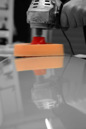Man polishing a metal panel with an electric buffer with selective color