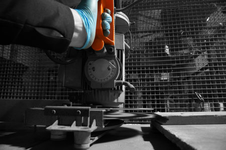 Man operating a circular saw on a workbench in a workshop with selective color