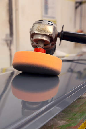 Electric industrial buffer with foam head reflected on a painted metal panel in a workshopの写真素材