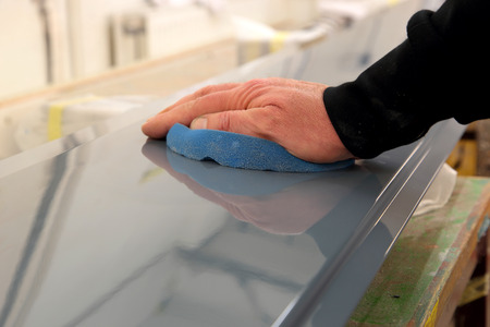 Man polishing a painted metal panel with a foam pad in a workshopの写真素材