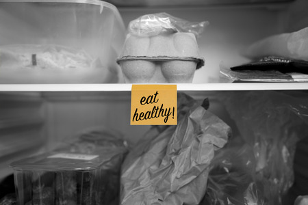 Eat healthy written on a  note stuck on a fridge shelf with food.  Abstract with selective colourの写真素材