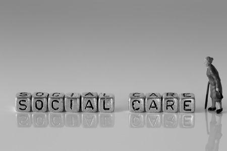 Miniature scale model senior pensioners talking with the word social care on beadsの写真素材