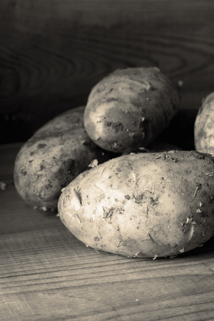Freshly picked dirty organic potatoes on a wooden background with toningの写真素材