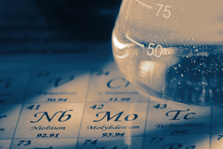 Chemicals in glass laboratory flask on the periodic table chart with colour toningの写真素材