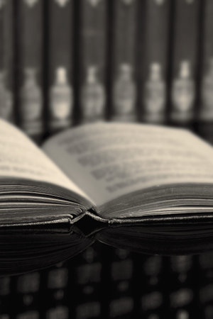 Book collection with an open book reflected on a black glass background with toning