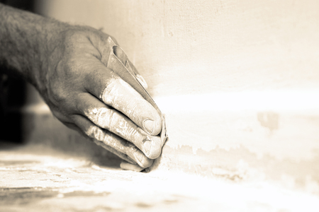 Man sanding a skirting board with sandpaper with colour toningの写真素材