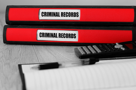 Red folders with criminal records written on the label on a desk with selective colourの写真素材