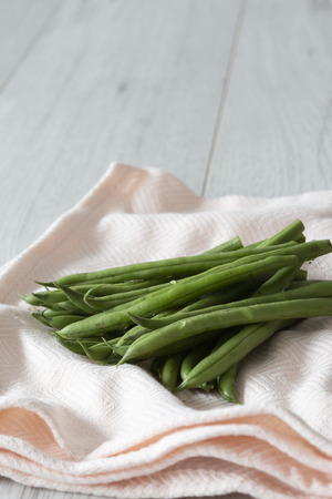 Green beans organic and freshly picked drying on a pink tea towel with grey wood backgroundの写真素材