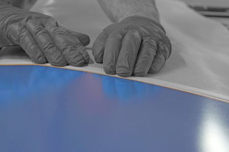 Man lining out metal panel with tape and covering with paper and masking tape.  Selective colour...