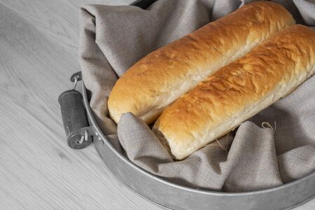 Baguettes, homemade freshly cooked, on cotton fabric on top of a metal tray with handles.の写真素材