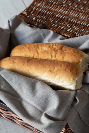 Baguettes, homemade freshly cooked, on cotton fabric on top of a wicker brown picnic basket