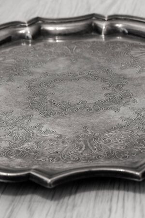 Antique tarnished silver tray with engraved pattern on a grey wood backgroundの写真素材