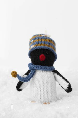 Penguin knitted toy Christmas decoration with hat and scarf on artificial snow. With a white backgroundの写真素材