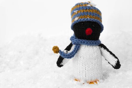 Penguin knitted toy Christmas decoration with hat and scarf on artificial snow. With a white backgroundの写真素材