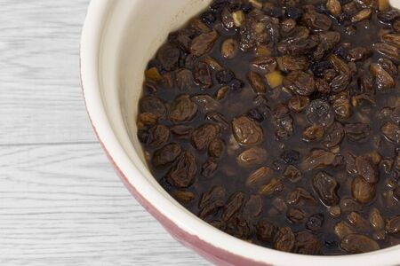 Mixed dried fruit soaking in a tea marinade in a mixing bowl. Grey wood backgroundの写真素材