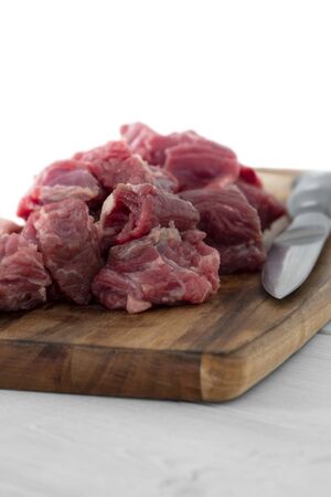 Beef brisket, diced cubed, on a wooden chopping board with a knife.  Grey wood backgroundの写真素材