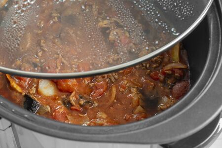 Bolognese sauce cooking in a slow cooker with glass lid lifted off.  Selective colourの写真素材
