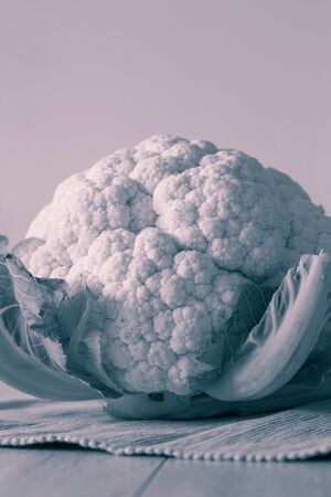 Cauliflower with leaves on a tea towel with a wood background.  with colour toningの写真素材