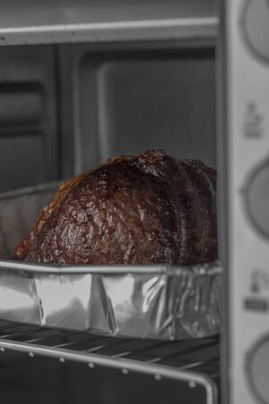 Beef topside joint cooking in a foil baking tray in an electric oven grill.の写真素材