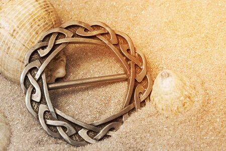 Silver antique old Celtic scarf ring with traditional design border in sand..  Hand made traditional jewellery conceptの写真素材