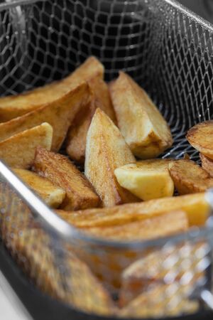 Chips cooking in vegetable oil in a deep fat fryer appliance.  Unhealthy fast food concept with a narrow depth of fieldの写真素材