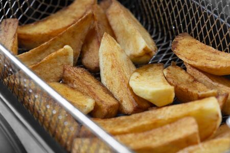 Chips cooking in vegetable oil in a deep fat fryer appliance.  Unhealthy fast food concept with a narrow depth of fieldの写真素材