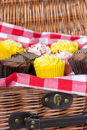 Variety of cupcakes in a wicker picnic basket.  With gingham clothの写真素材