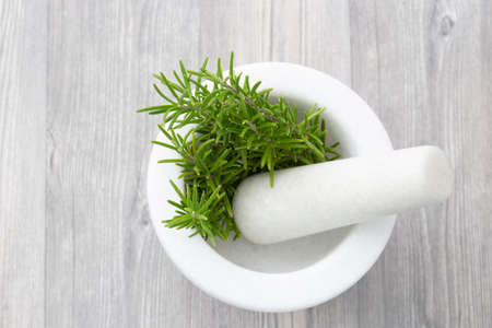 Rosemary in a white granite pestle and mortar.  Grey wood backgroundの写真素材