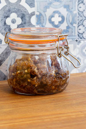 Mincemeat sealed in a clip glass jar.  On a wood worktop with a tiled backgroundの写真素材