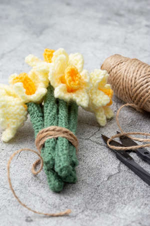 Knitted wool daffodil flowers with garden cutters and string.  On a concrete backgroundの写真素材